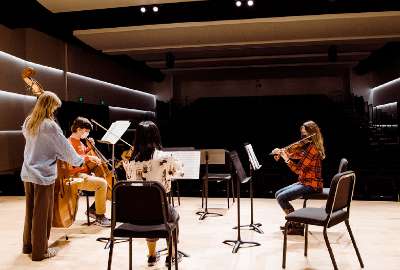 A strings quartet practicing on the Simon Concert Hall stage at the Omaha Conservatory.